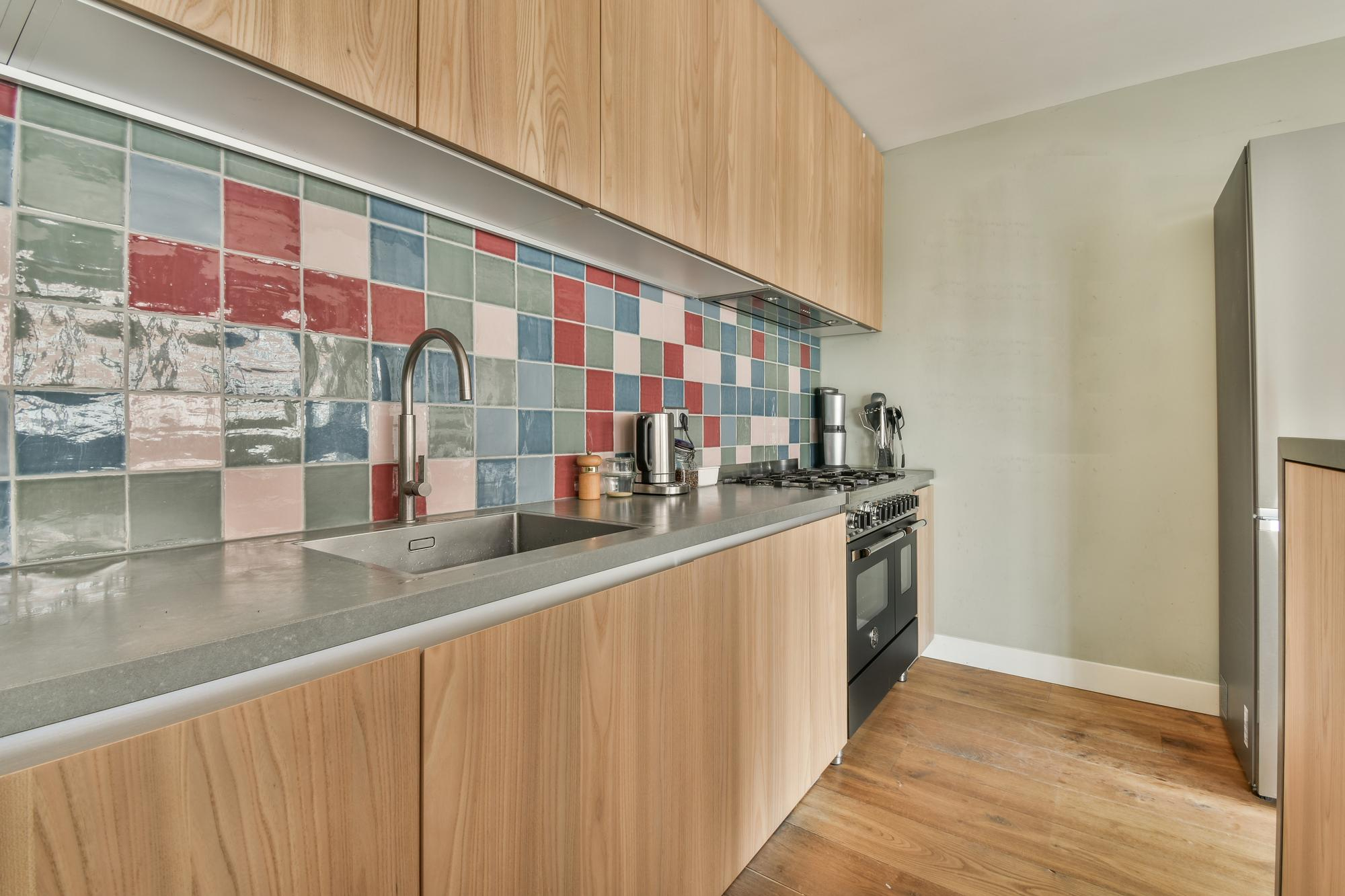 Colorful tiled backsplash with light wood kitchen cabinets