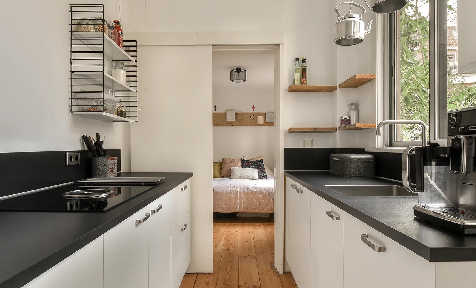 Compact galley kitchen with window and wall shelves