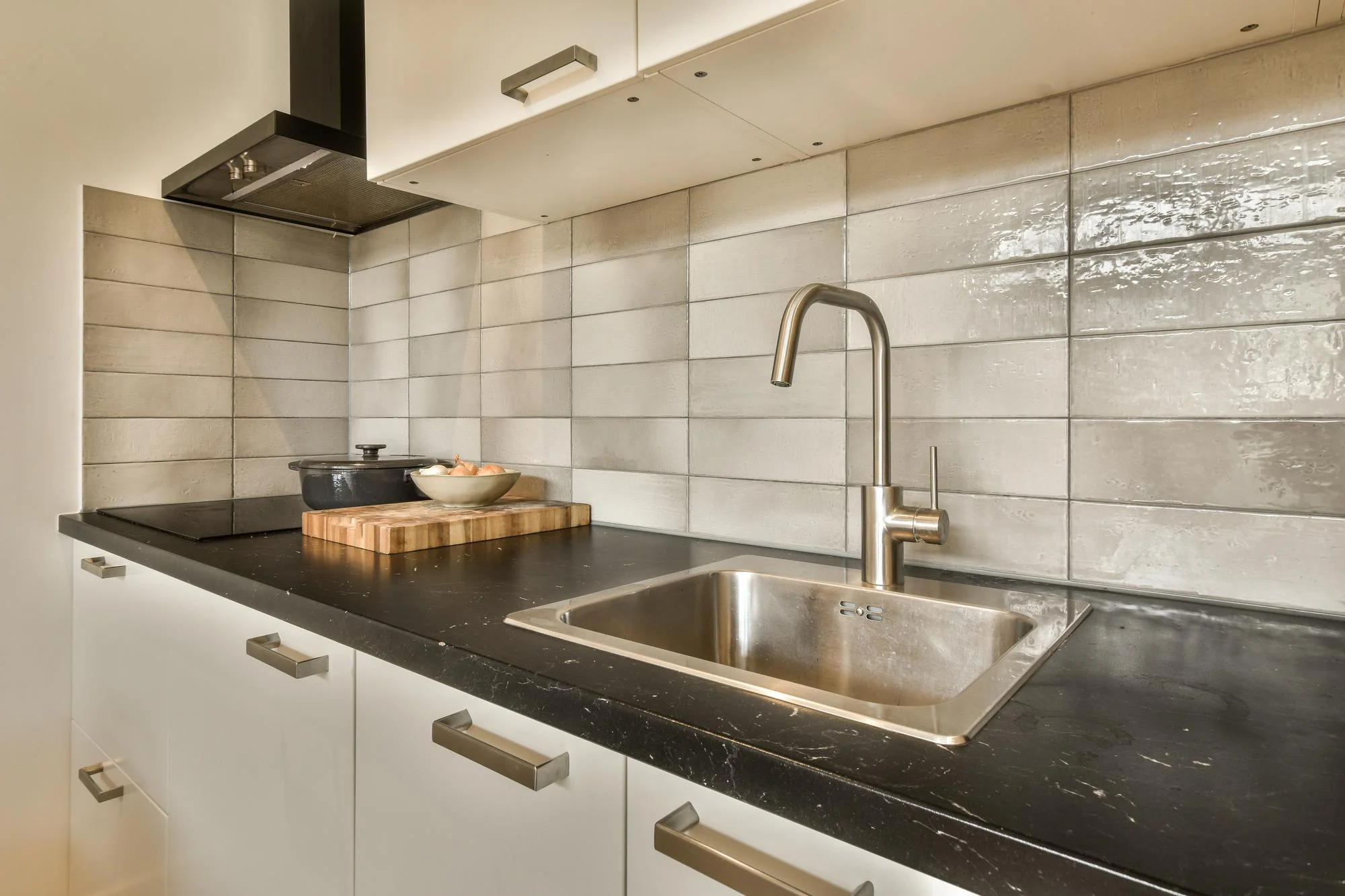Textured grey rectangular tiles behind modern sink