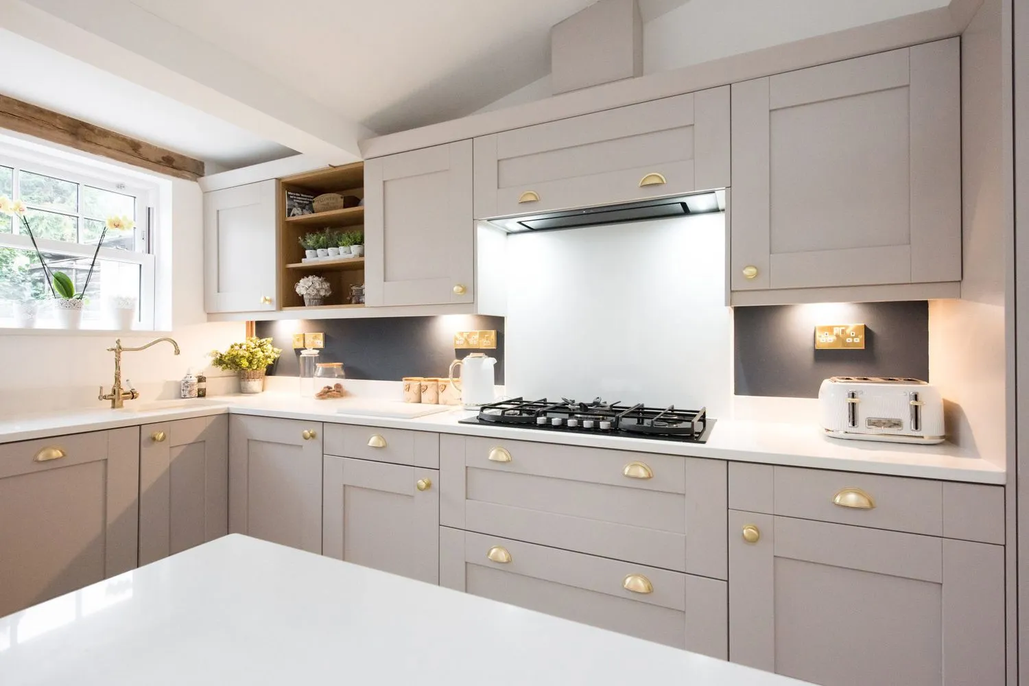 Warm grey shaker kitchen with brass hardware and soft lighting