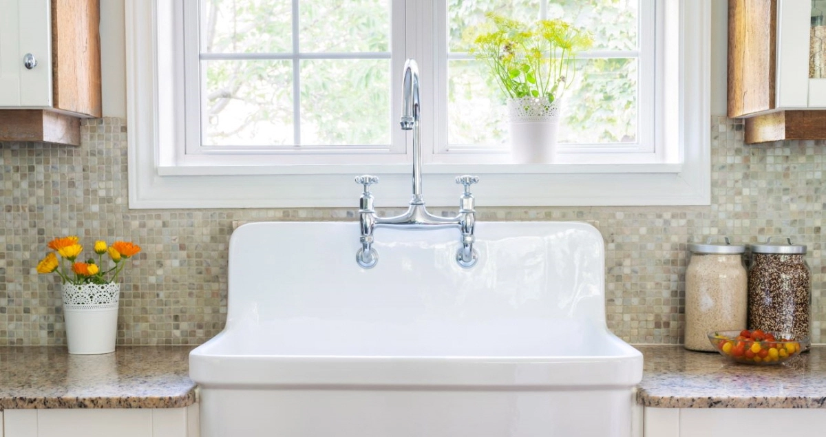 White farmhouse sink with chrome faucet by a window