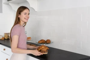 Woman preparing pastries on black kitchen countertop