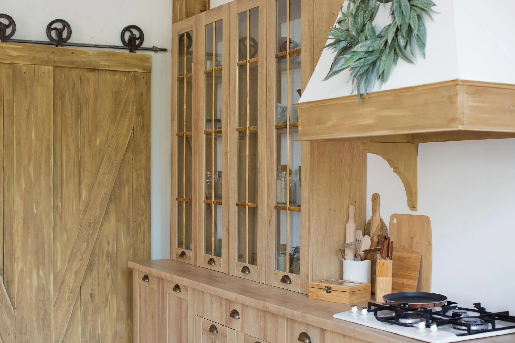 Light oak cabinets with glass doors and black handles