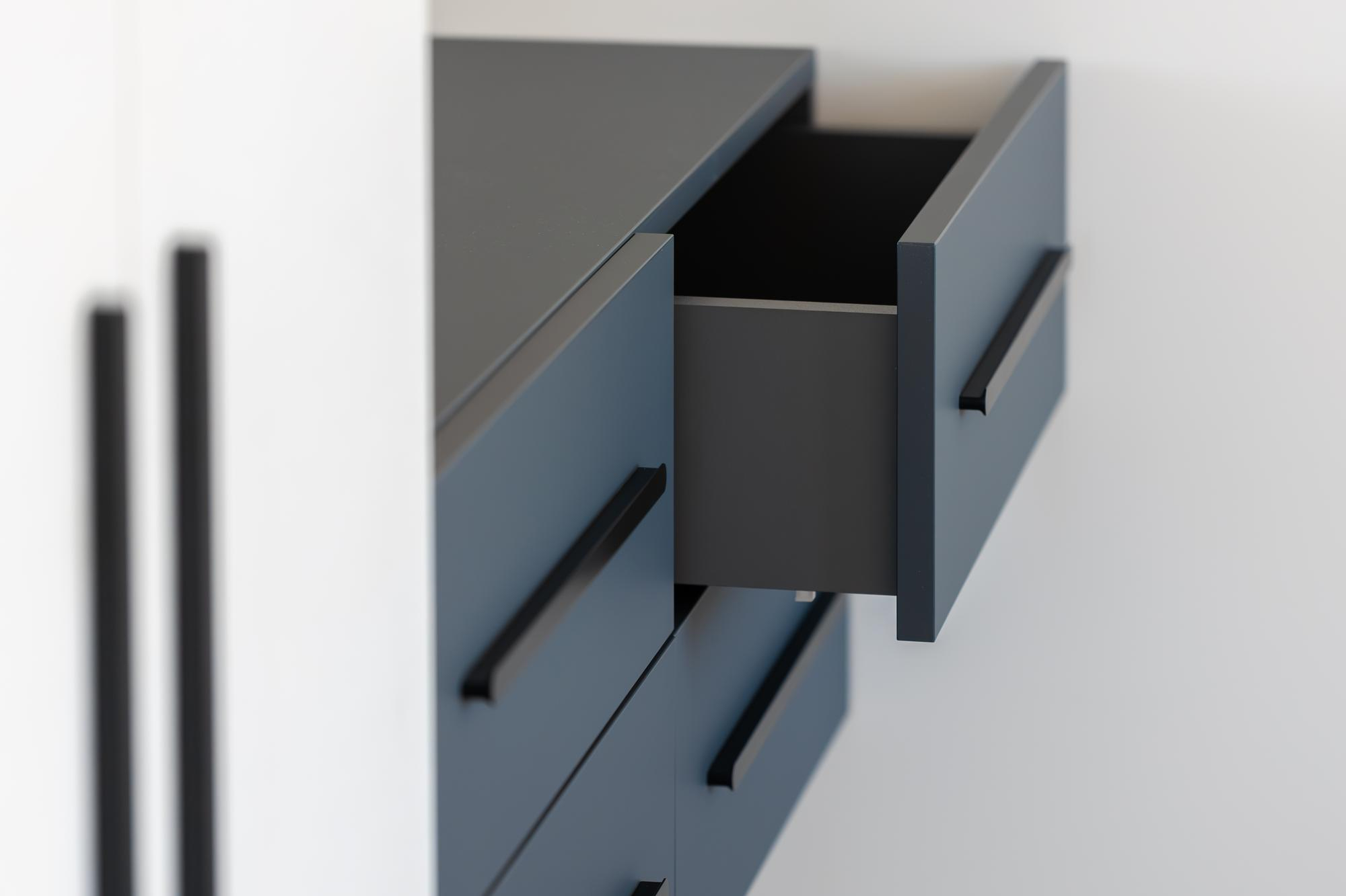 Open drawer with black pull on sleek blue cabinet