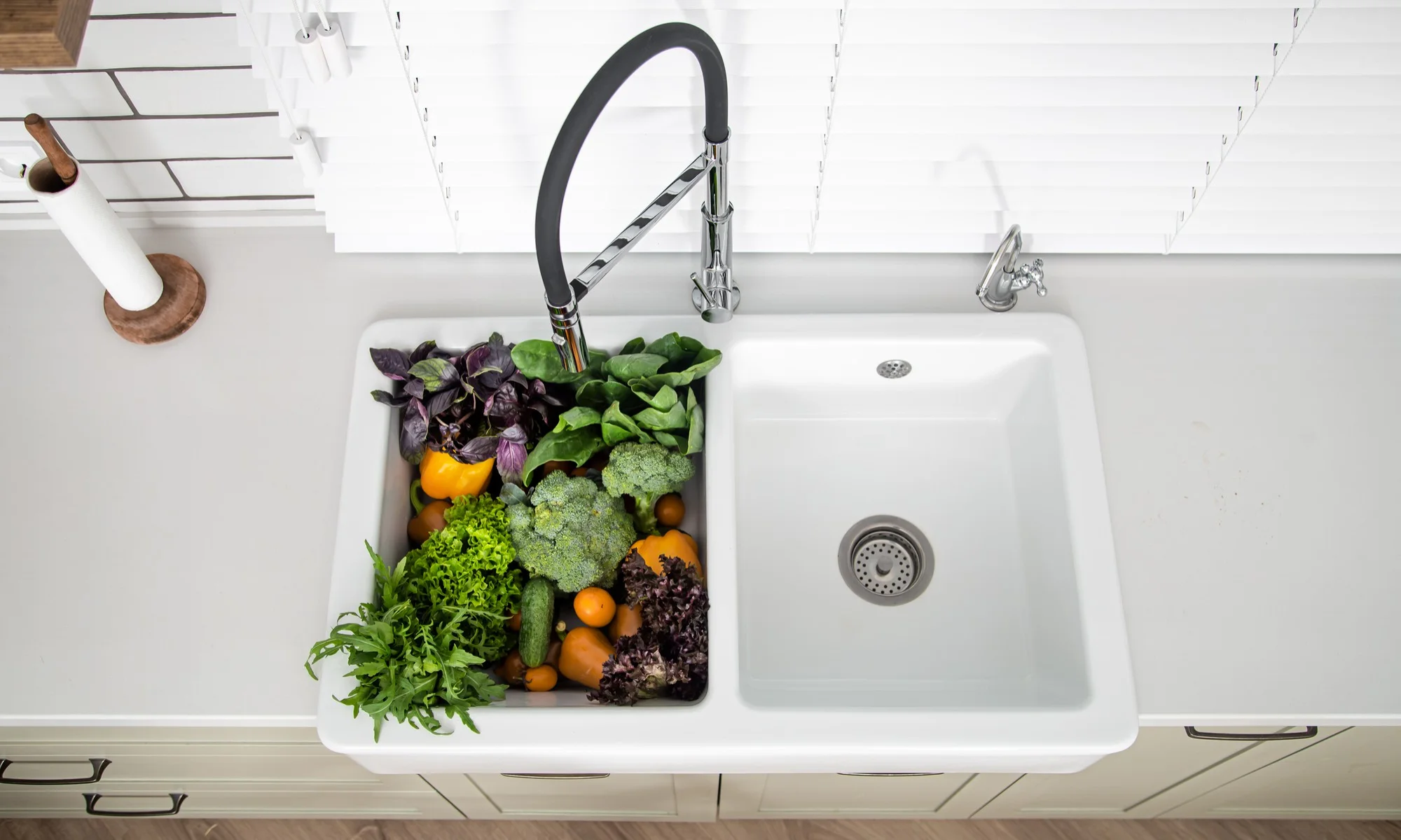 White kitchen sink with fresh vegetables inside