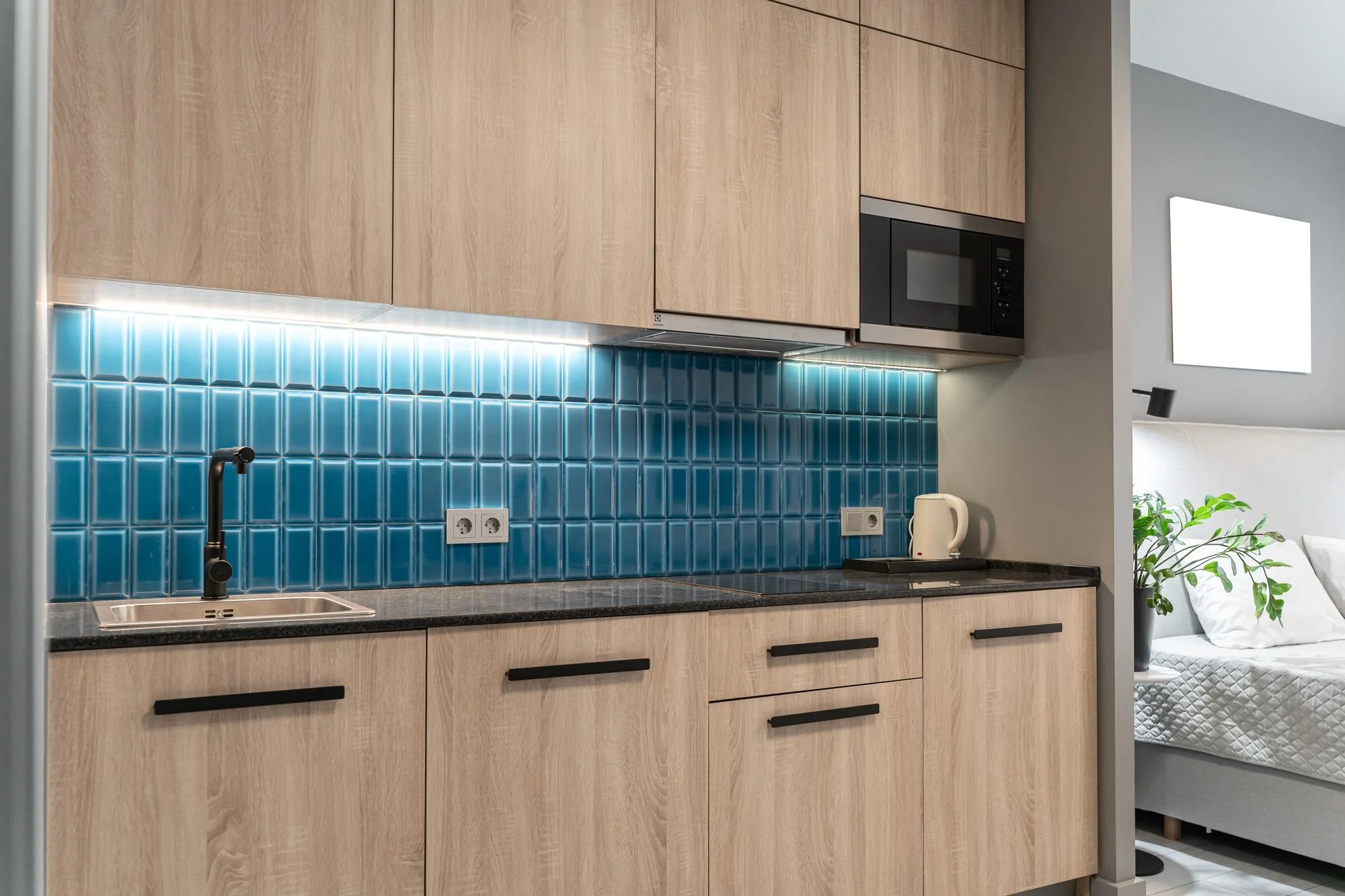 Wood tone kitchen with blue tile backsplash and underlights