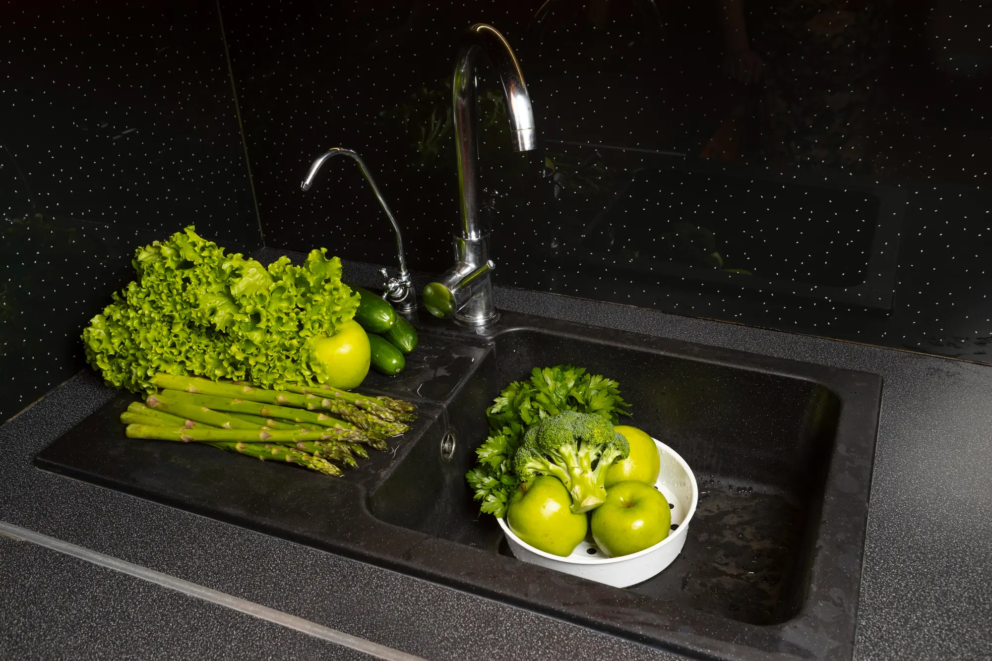 Black kitchen sink with vegetables and pull down faucet