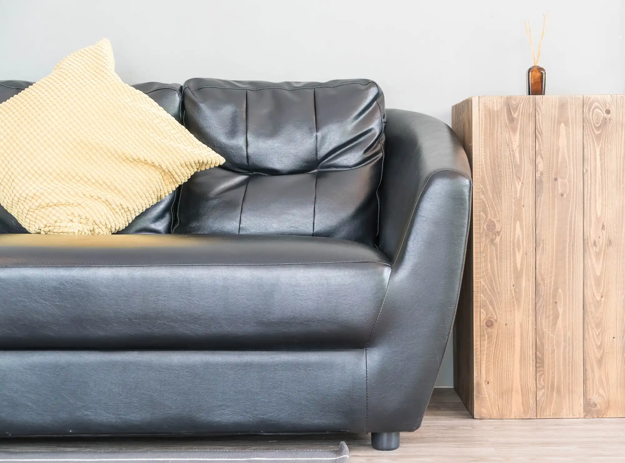Black leather sofa paired with wood side table