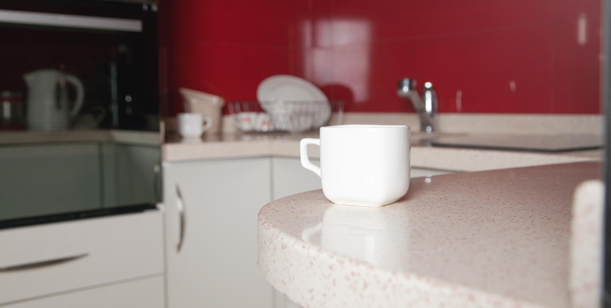 Close up of a beige quartz countertop and a white mug