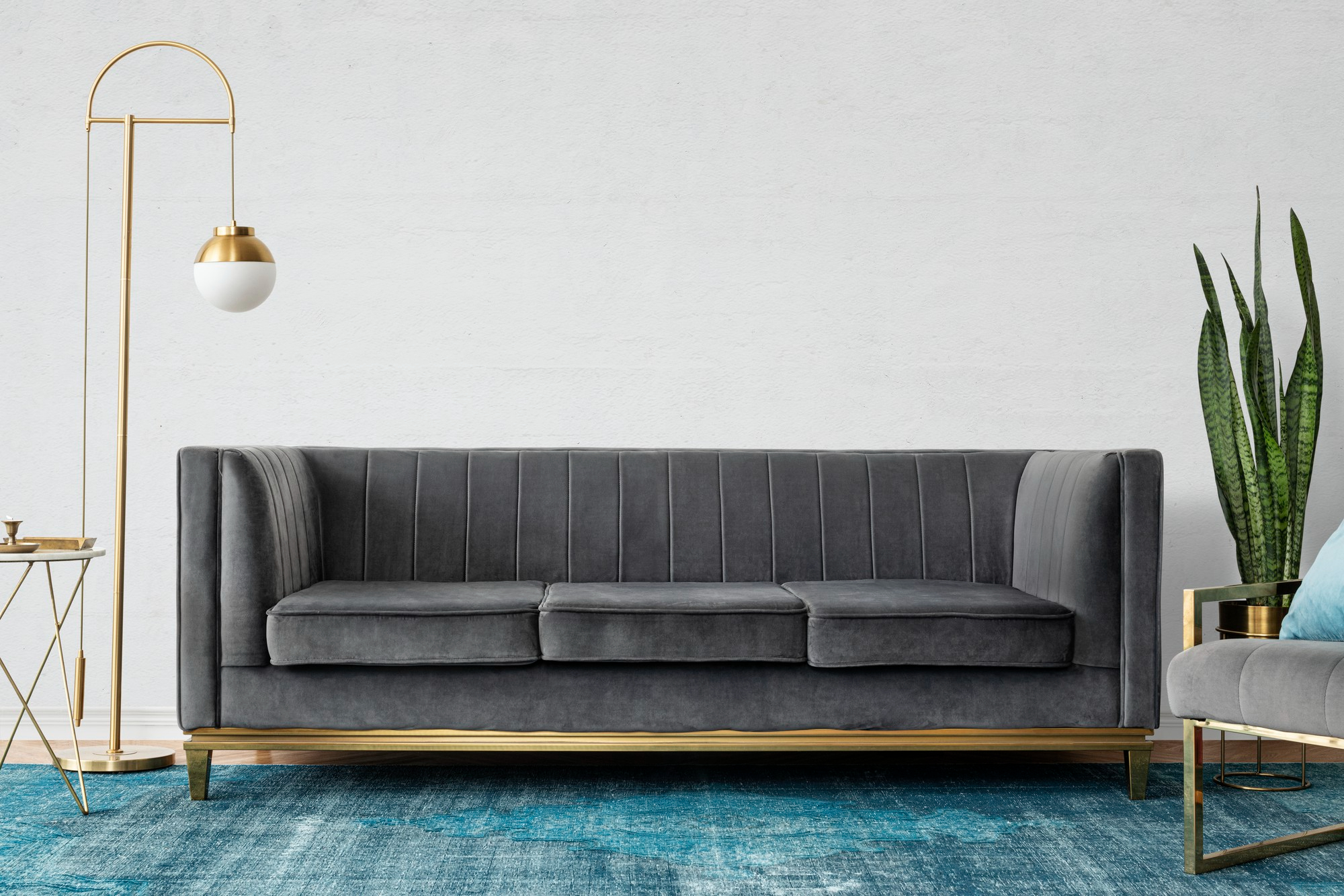 Modern gray velvet sofa with gold accents in a living room