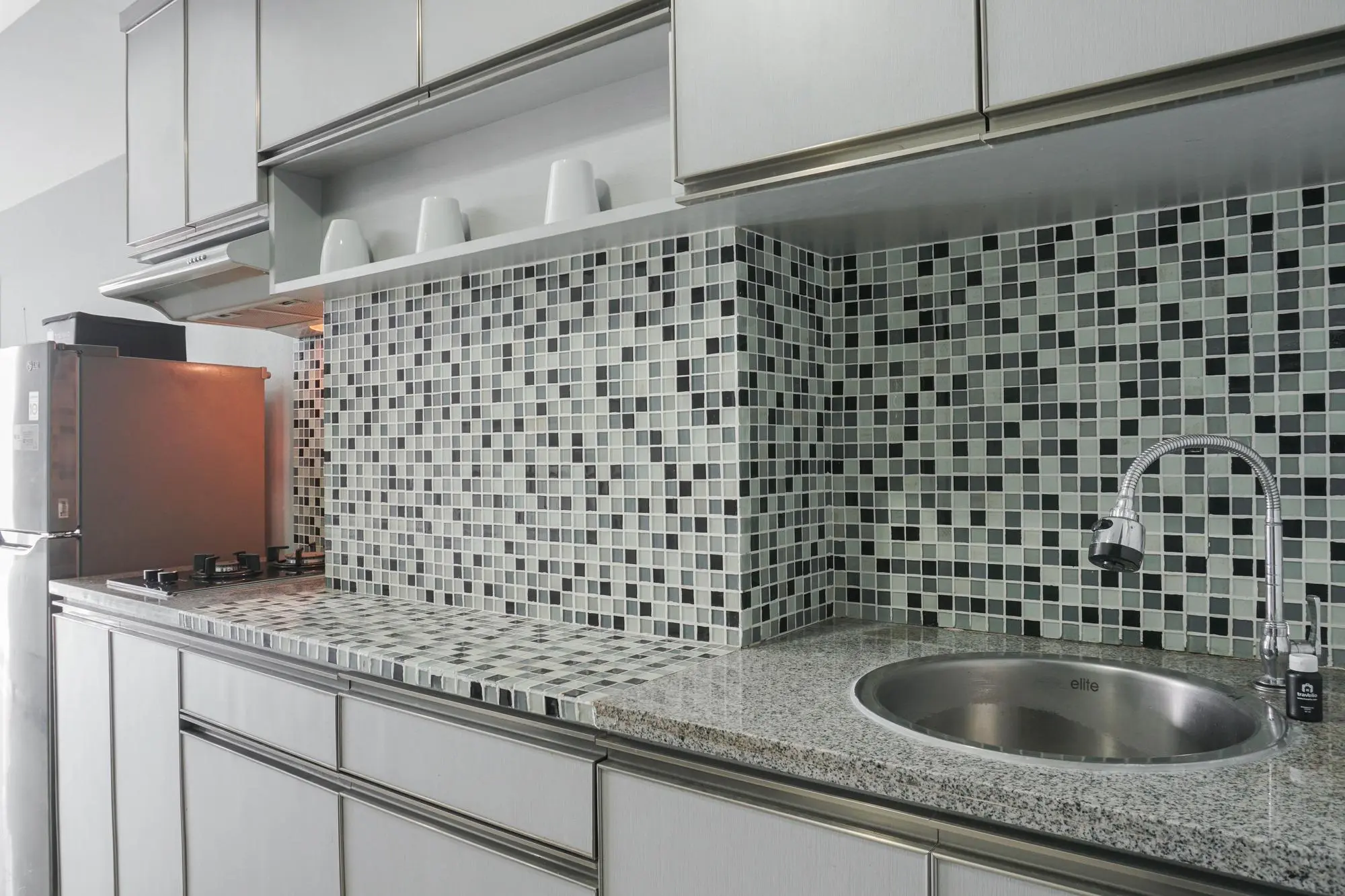Modern kitchen with mosaic backsplash and sink area, tile countertop