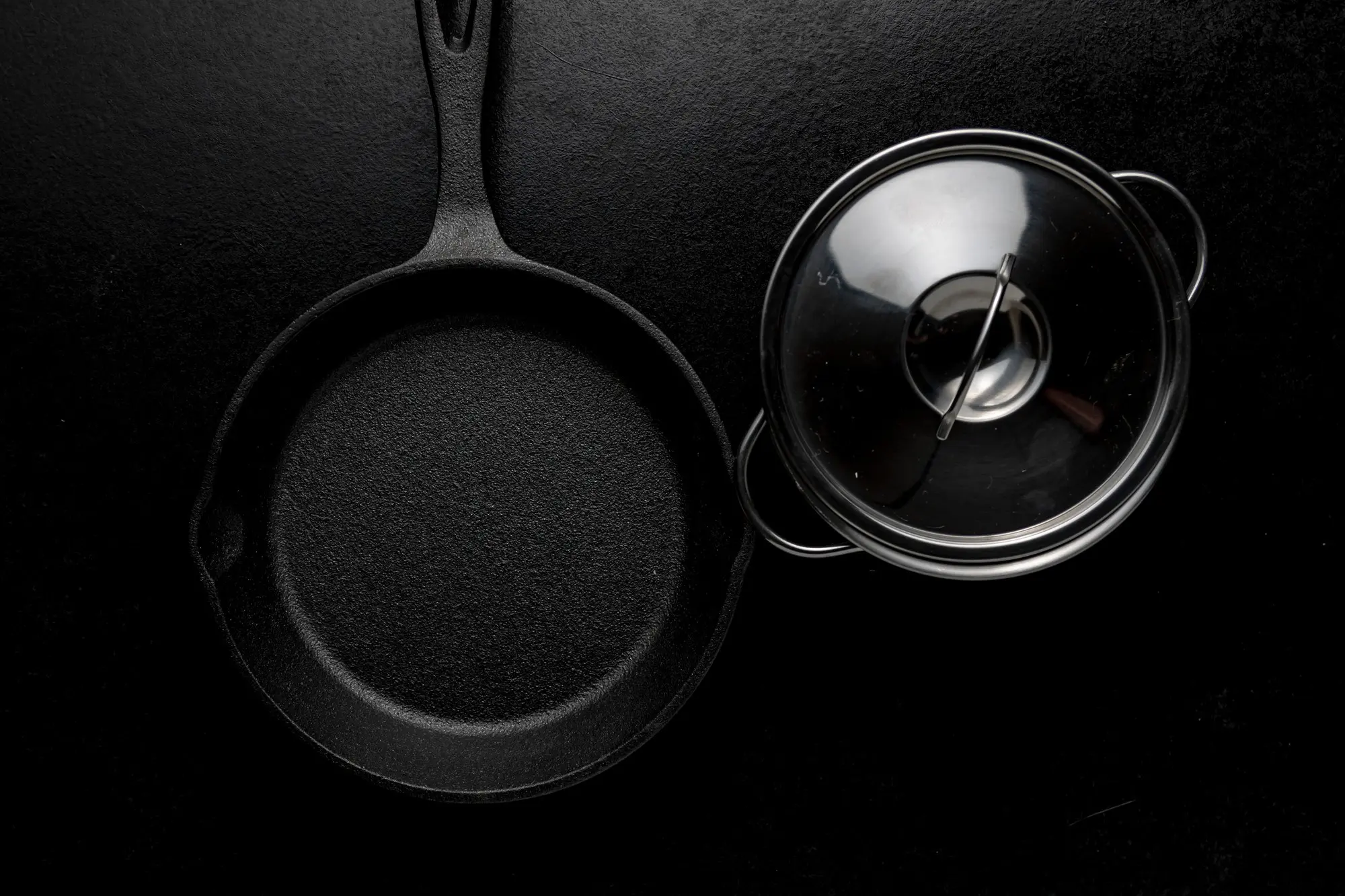 Sartén y olla de hierro fundido sobre fondo negro