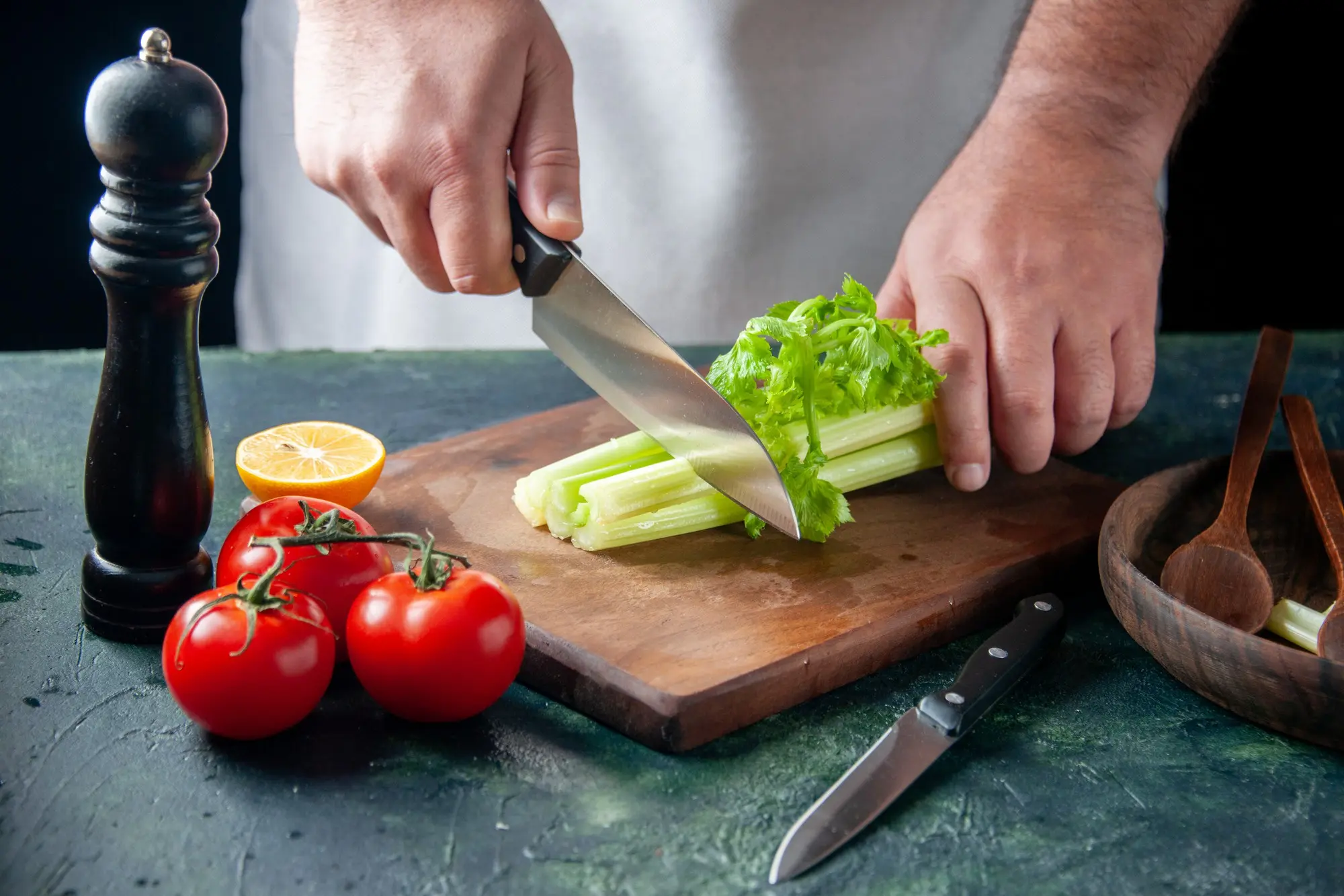 Chef cortando apio en una tabla de madera