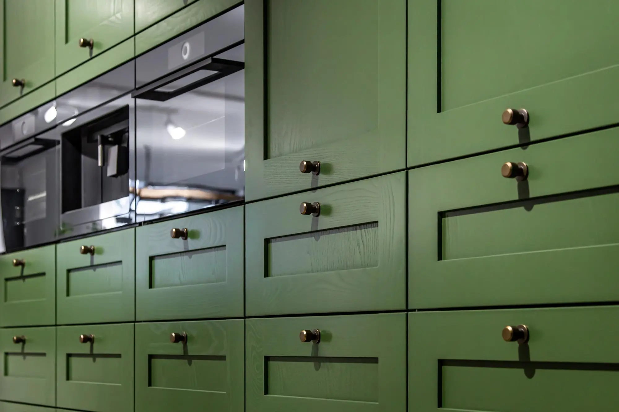 Green shaker kitchen cabinets with brass handles