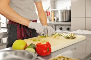 Chef slicing vegetables with gloves in clean kitchen
