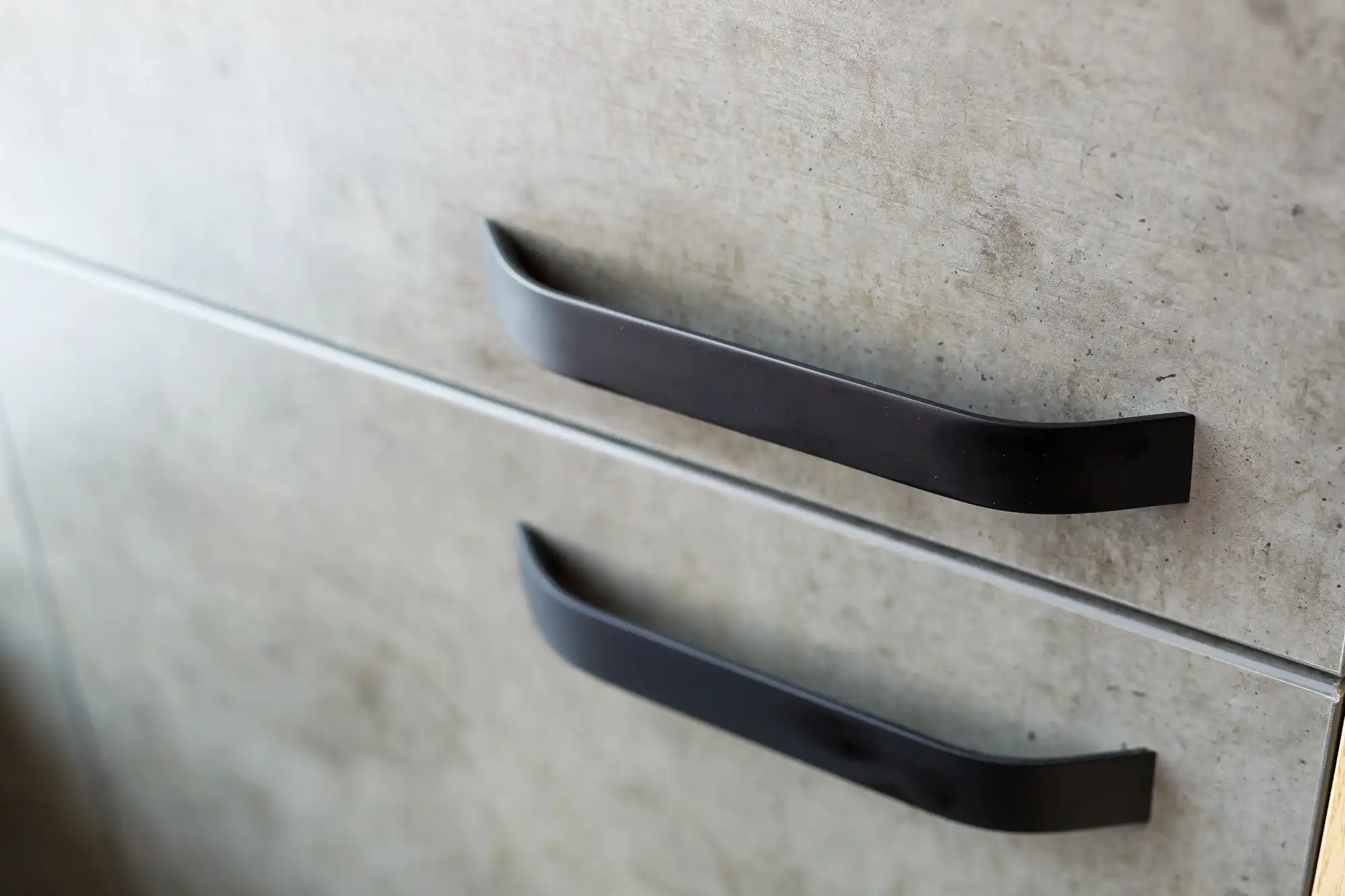 Close up of black drawer pulls on textured cabinet