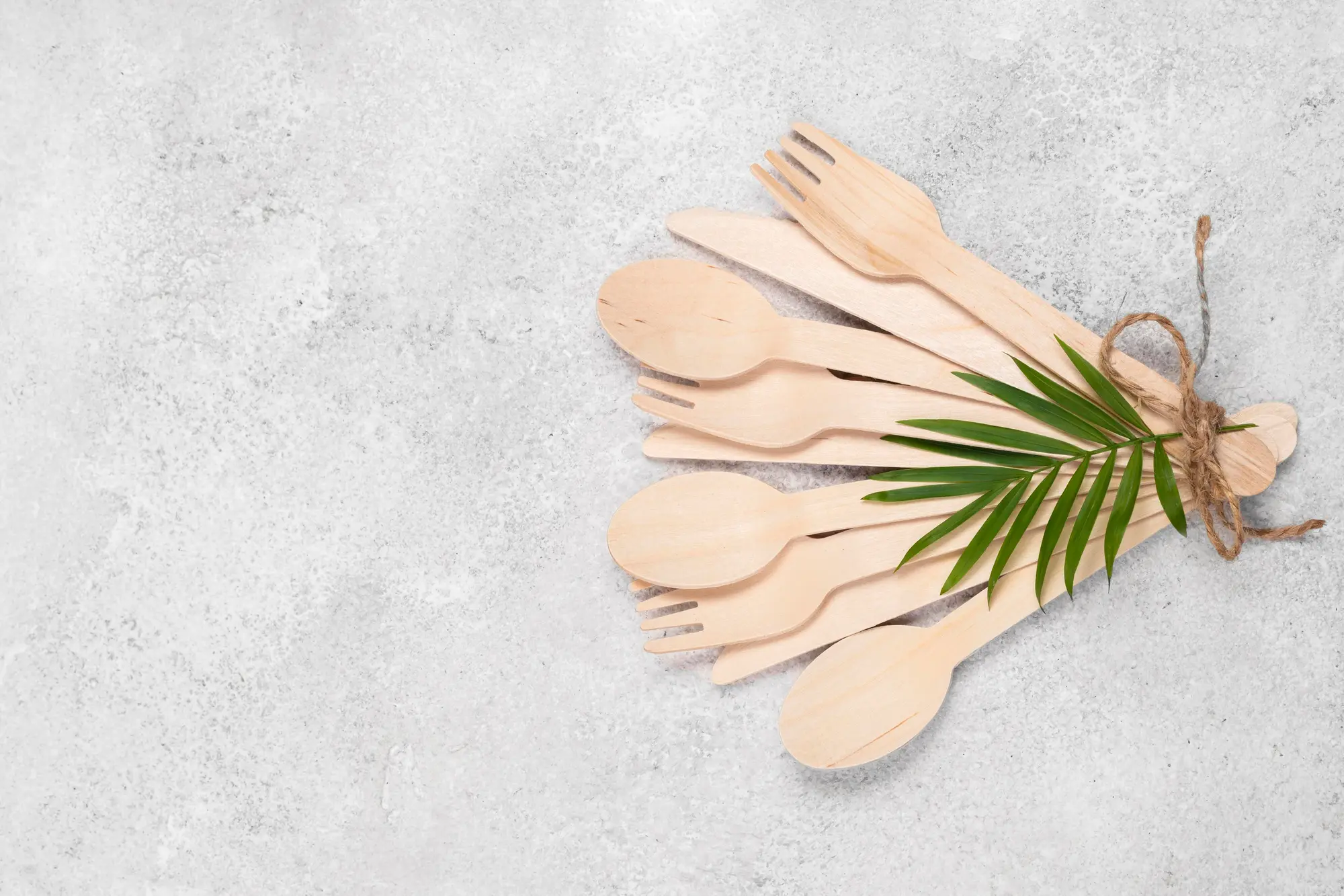 Eco bamboo utensils bundle with leaf on grey background