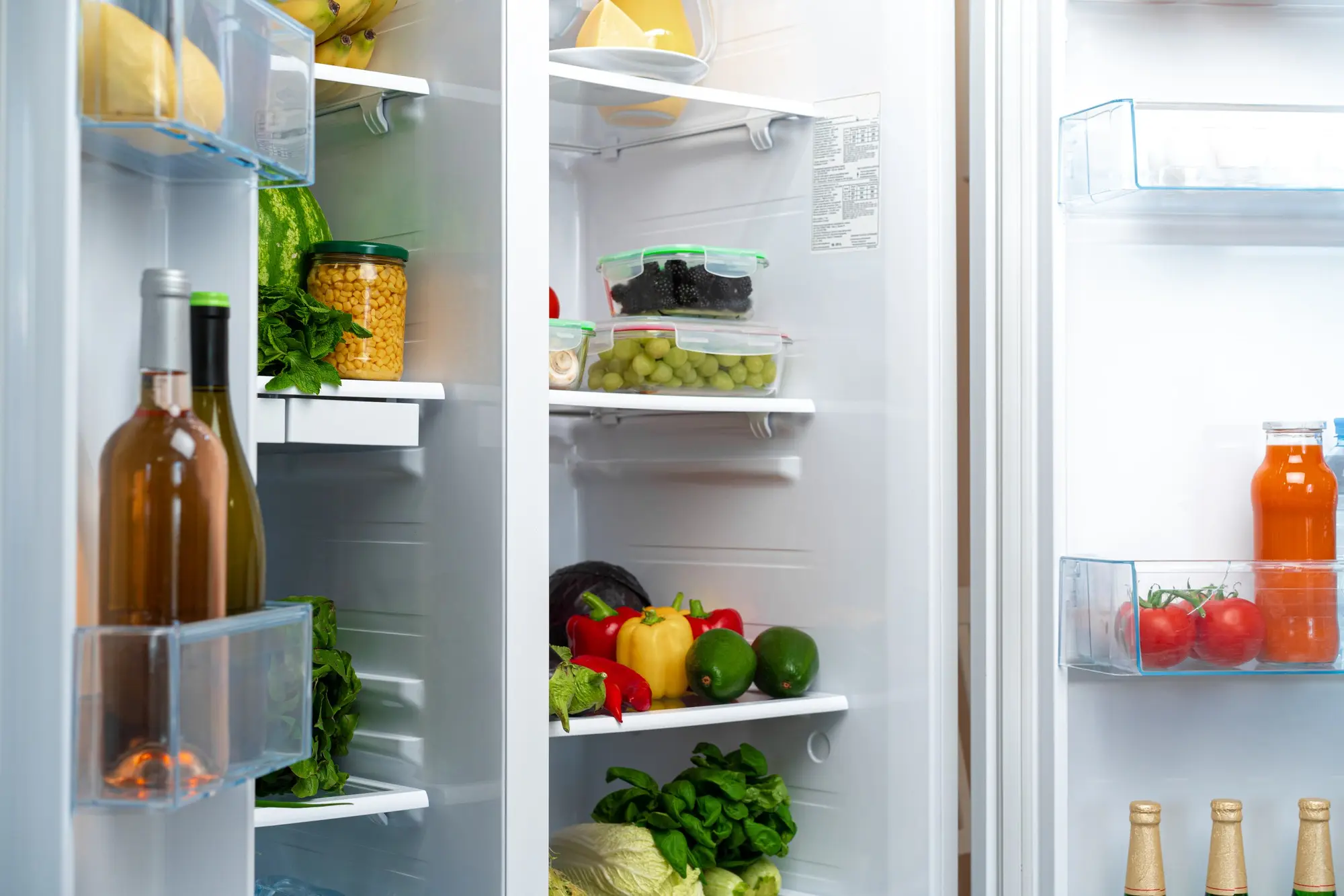 Open fridge with fresh vegetables and organized containers