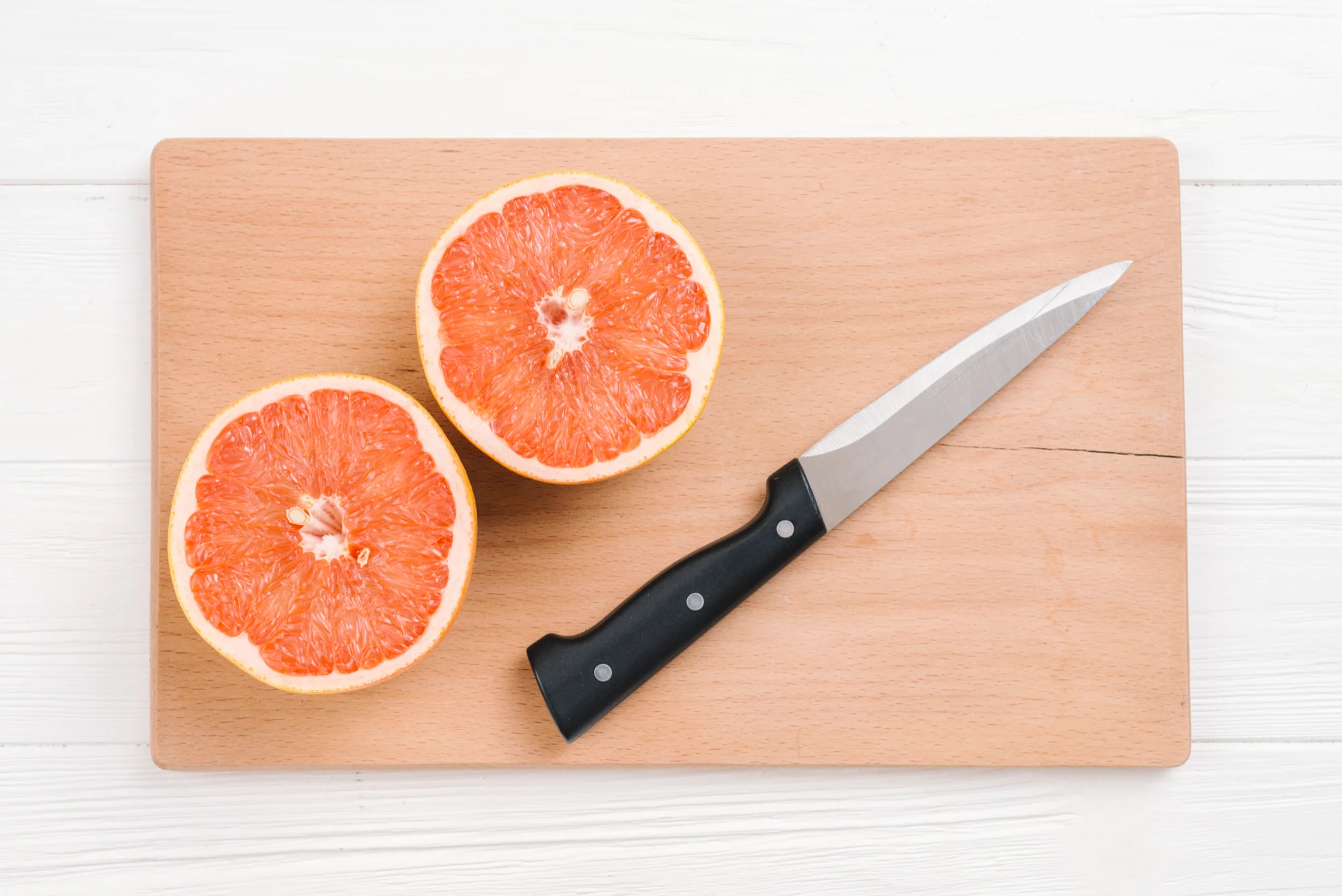Paring knife with grapefruit on cutting board