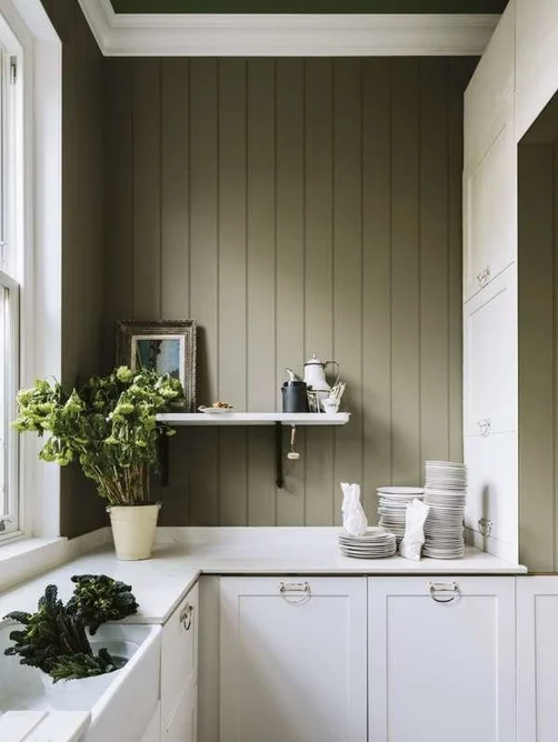 Sage green wall with white cabinets and natural accents