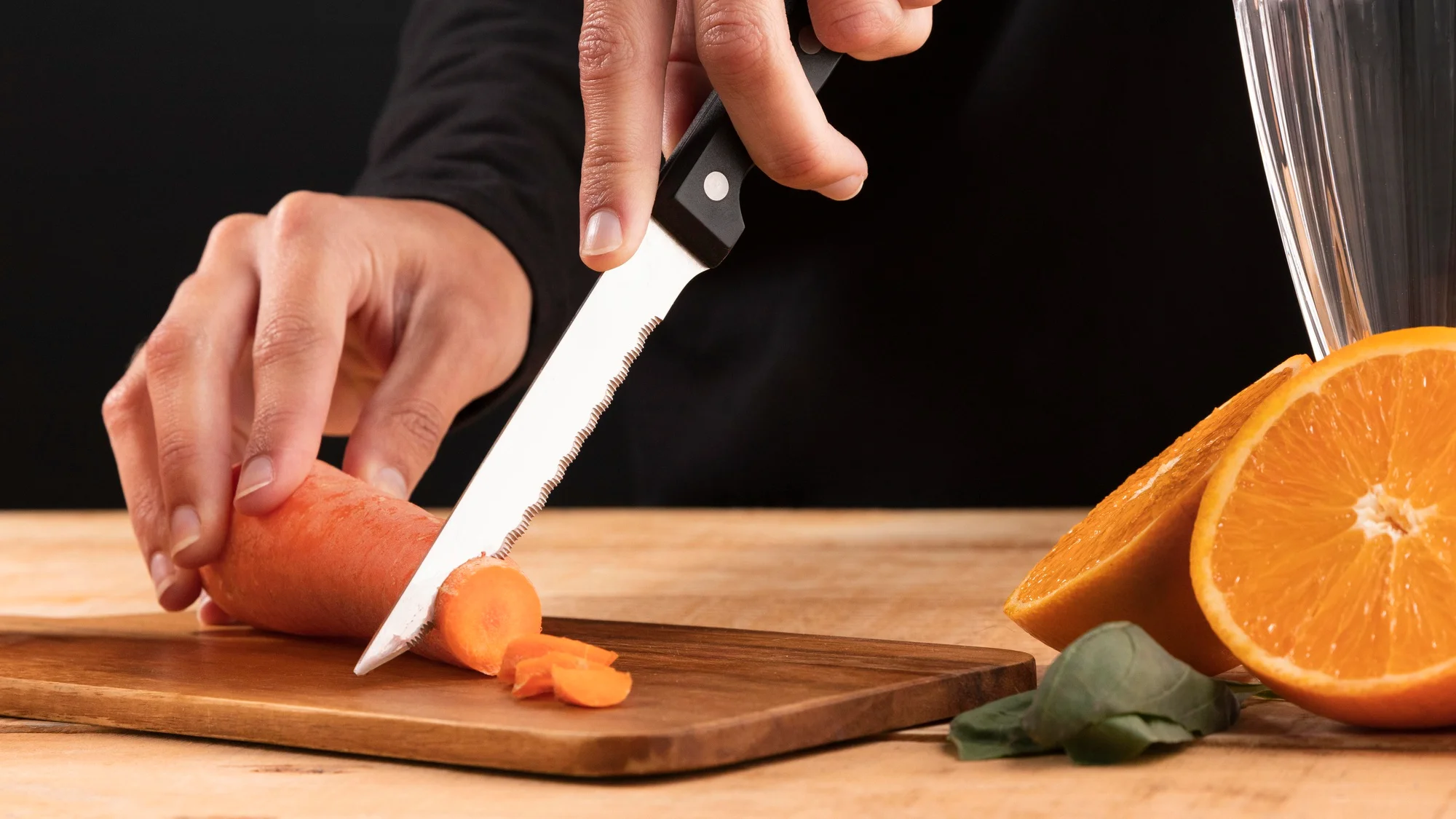 Slicing knife cutting carrot on wooden board