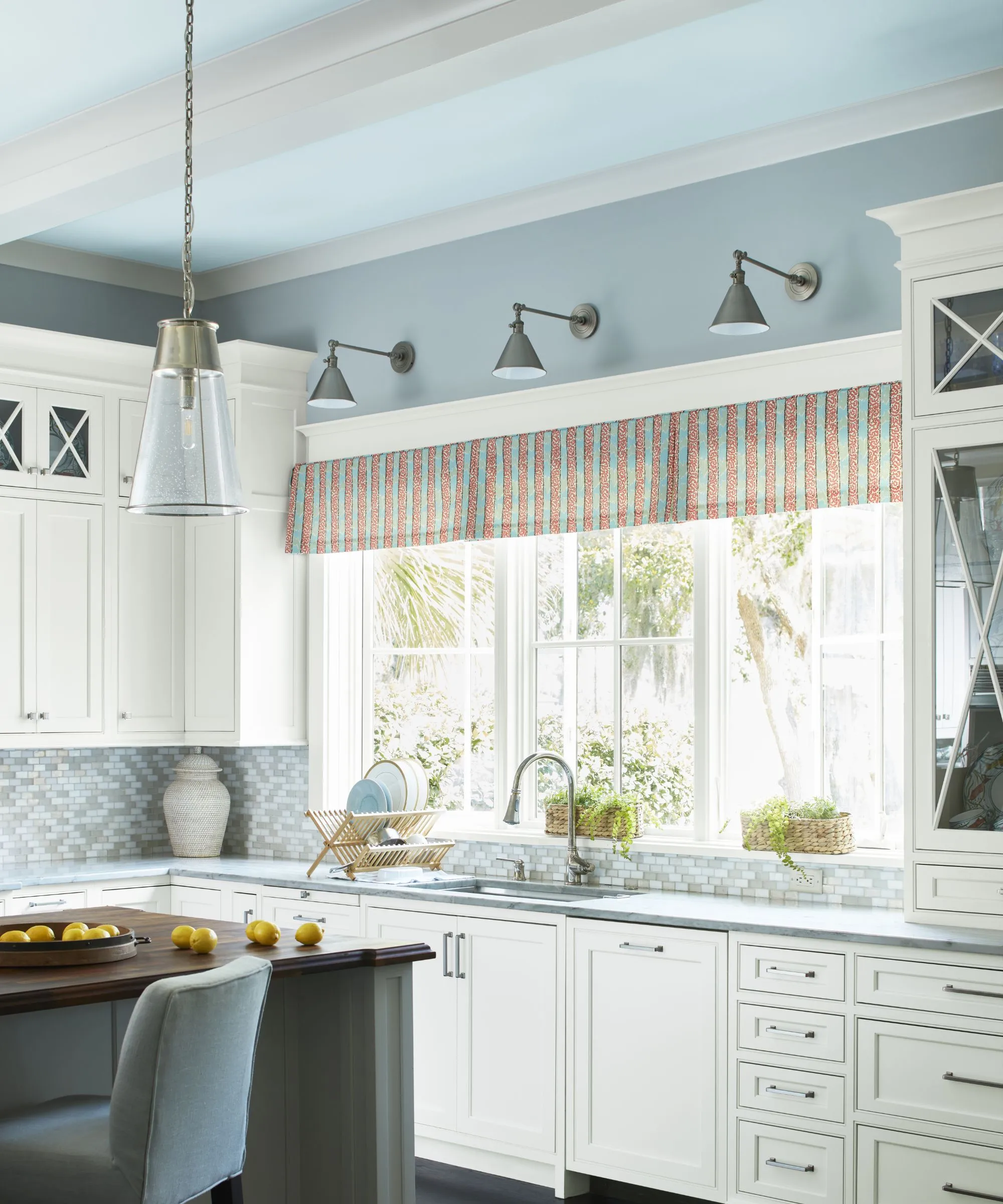 Soft blue wall with white kitchen cabinets and natural light