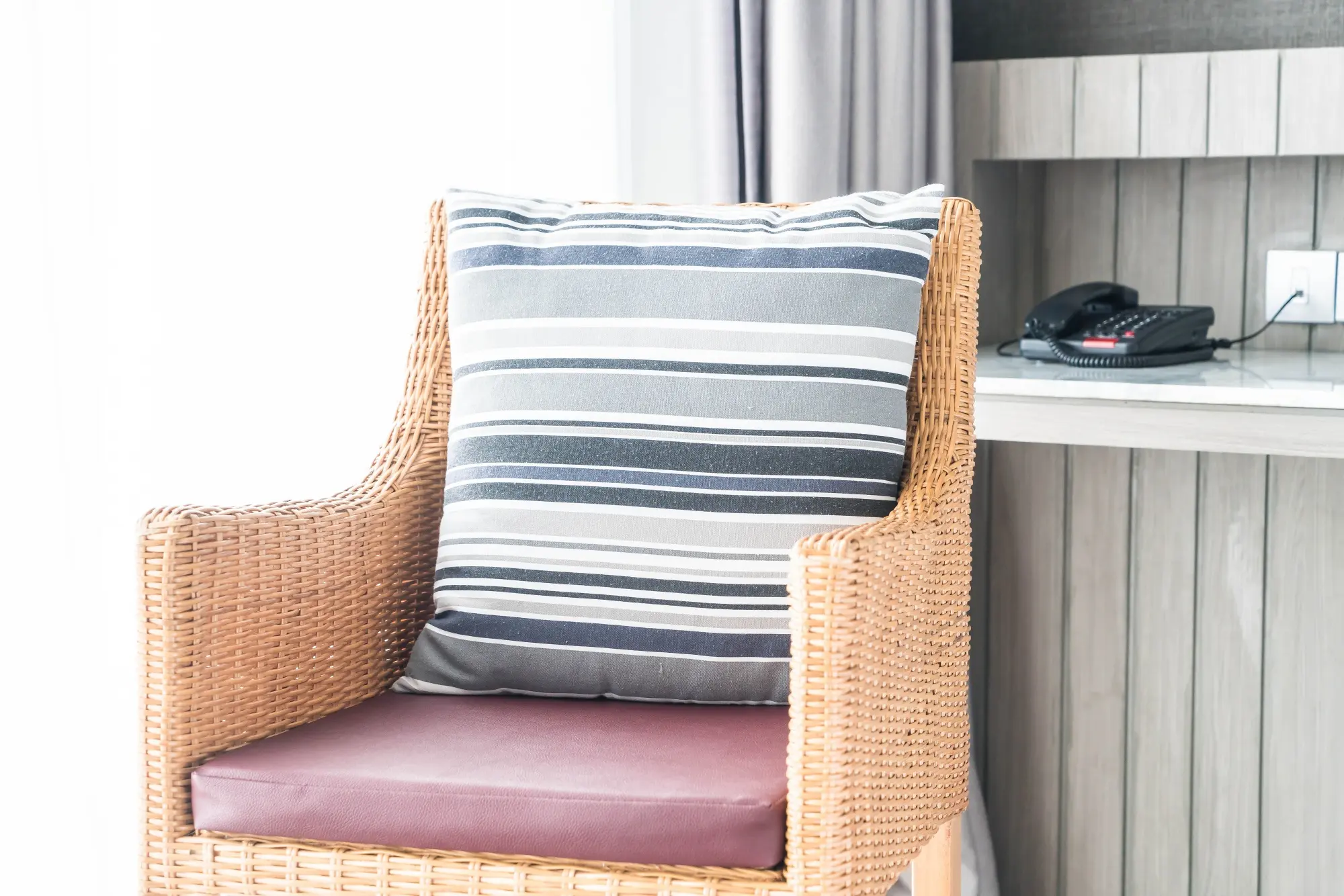 Fauteuil en osier avec coussin rayé dans une pièce moderne