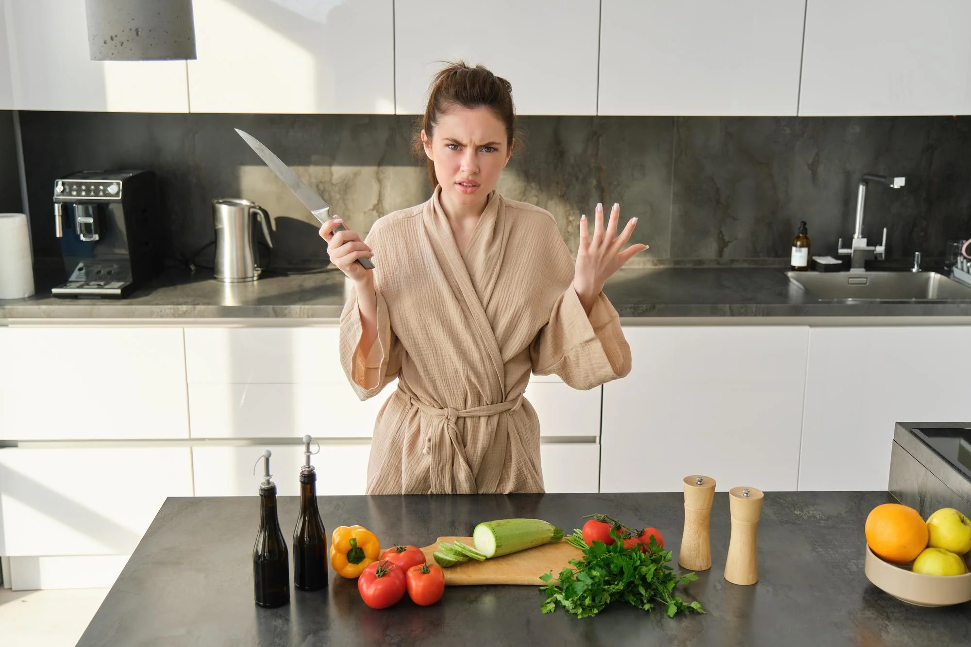 Woman holding knife in kitchen looking confused cooking