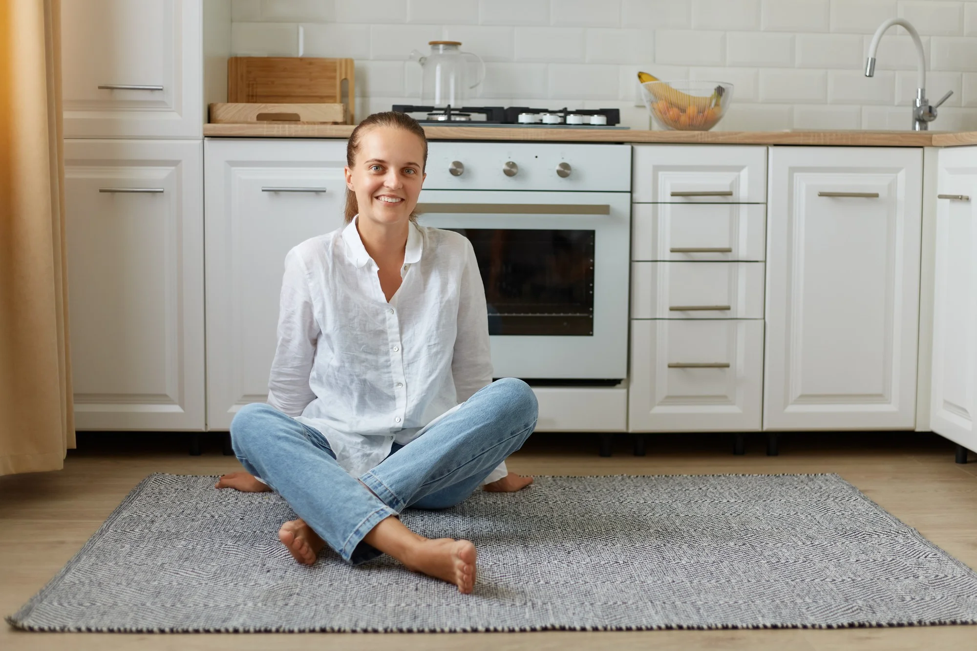 Femme assise sur un tapis moelleux dans une cuisine intérieure confortable Femme assise sur un tapis moelleux dans une cuisine intérieure confortable