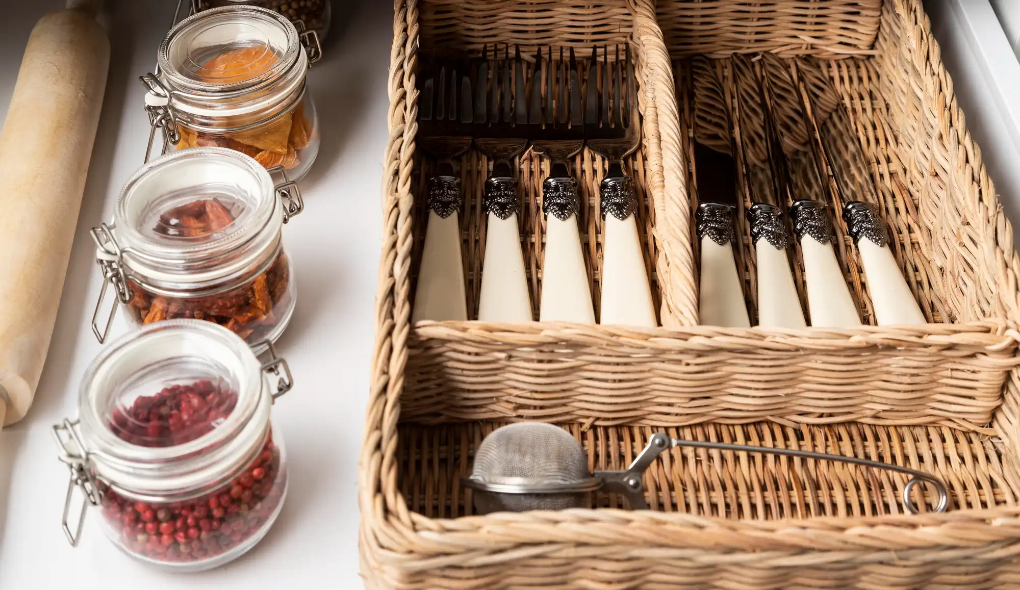 Panier à ustensiles tressé contenant des couverts et des bocaux en verre