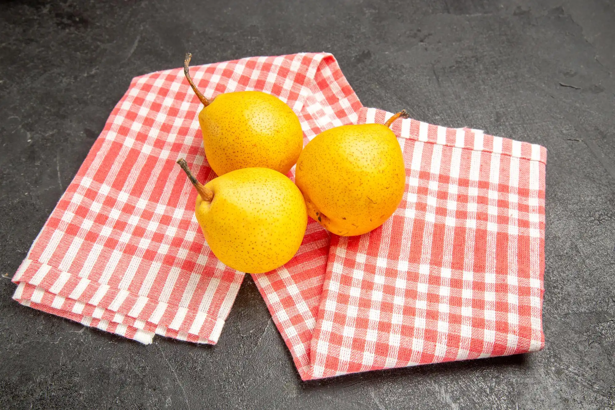 Poires jaunes sur des serviettes en tissu à carreaux rouges