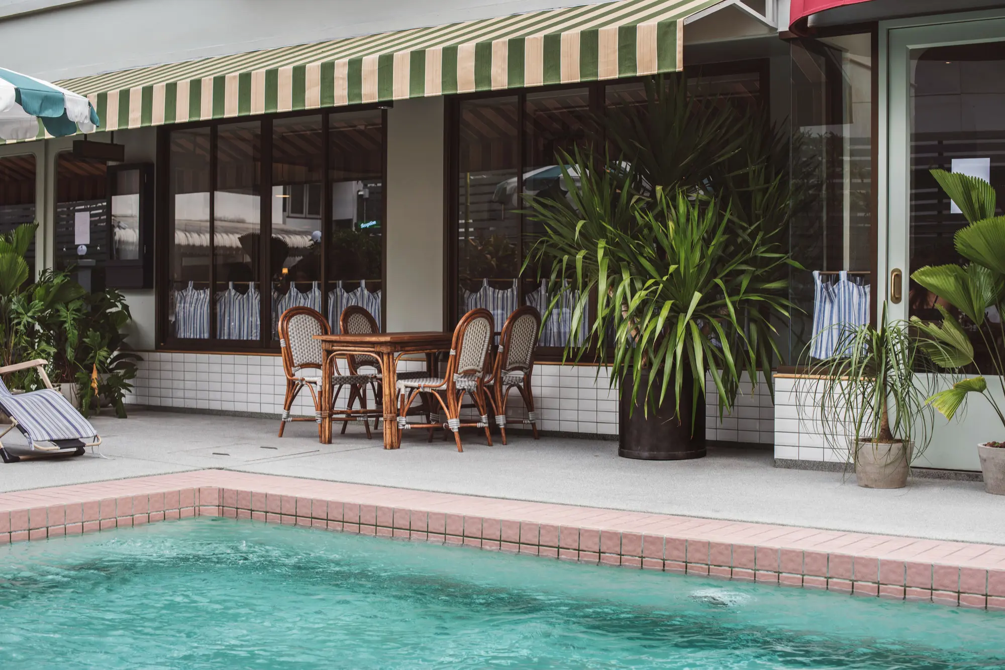 Casual poolside dining area with a green striped awning, Poolside Outdoor Kitchen