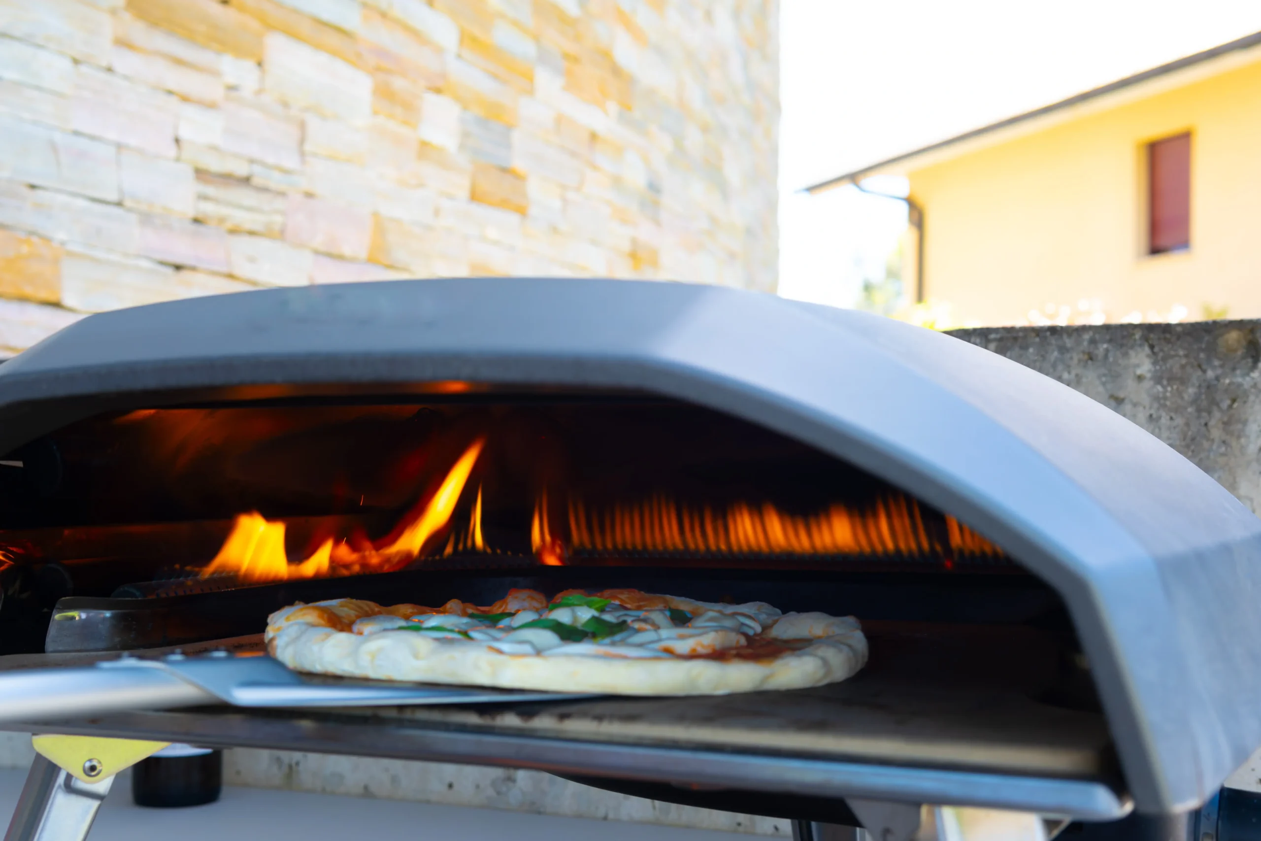 Fresh pizza baking inside a portable outdoor pizza oven, Outdoor Kitchen with Pizza Oven