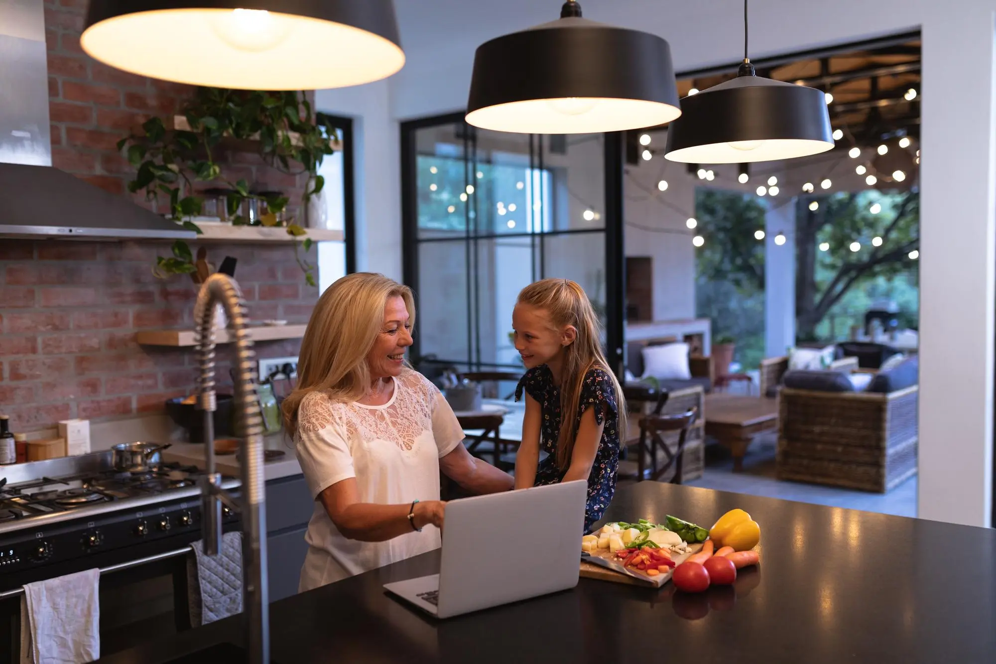 Grandmother and girl using laptop in a cozy kitchen, Indoor Outdoor Connected Kitchen