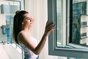 Woman opening modern casement window in apartment