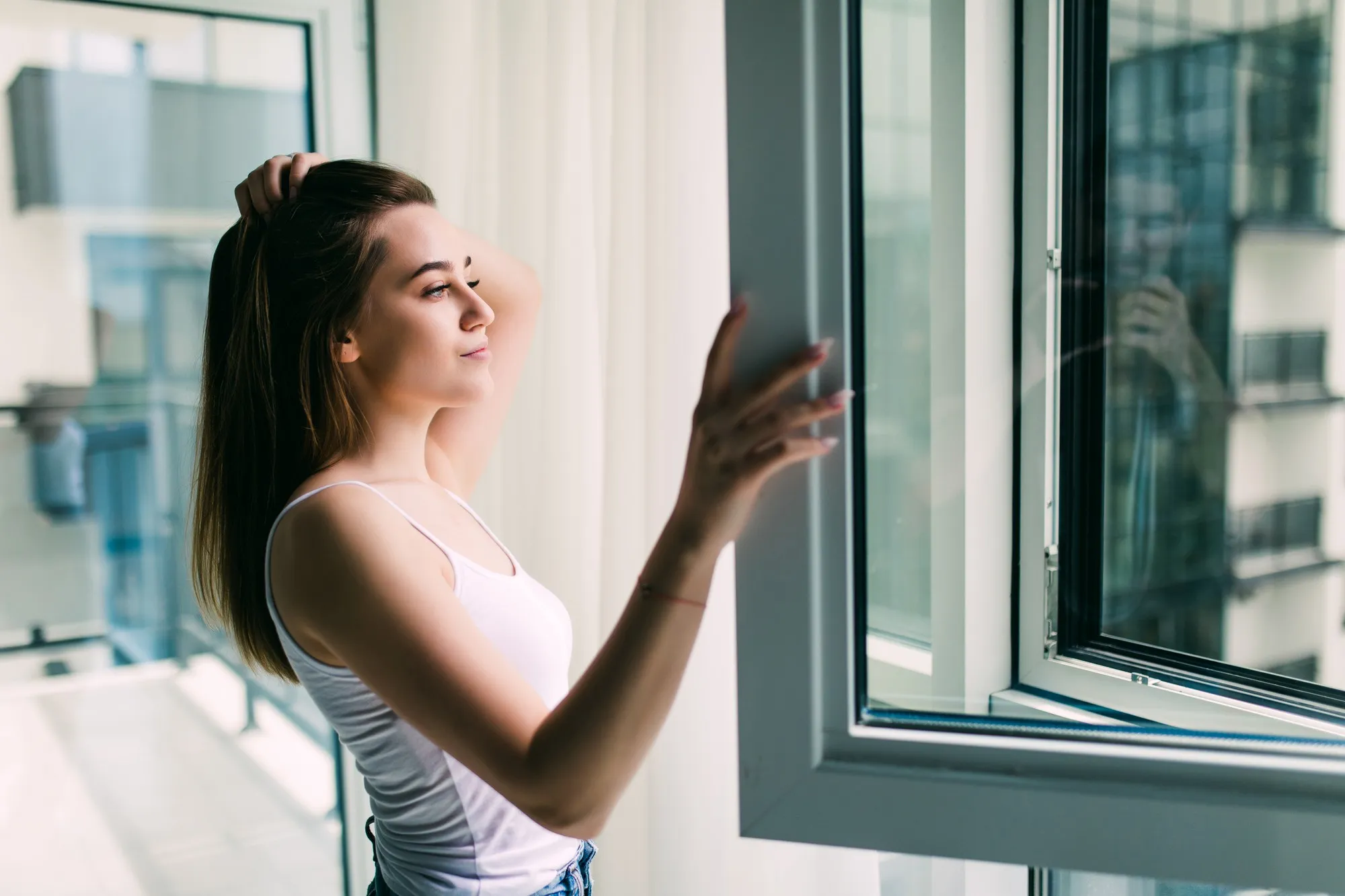 Woman opening modern casement window in apartment