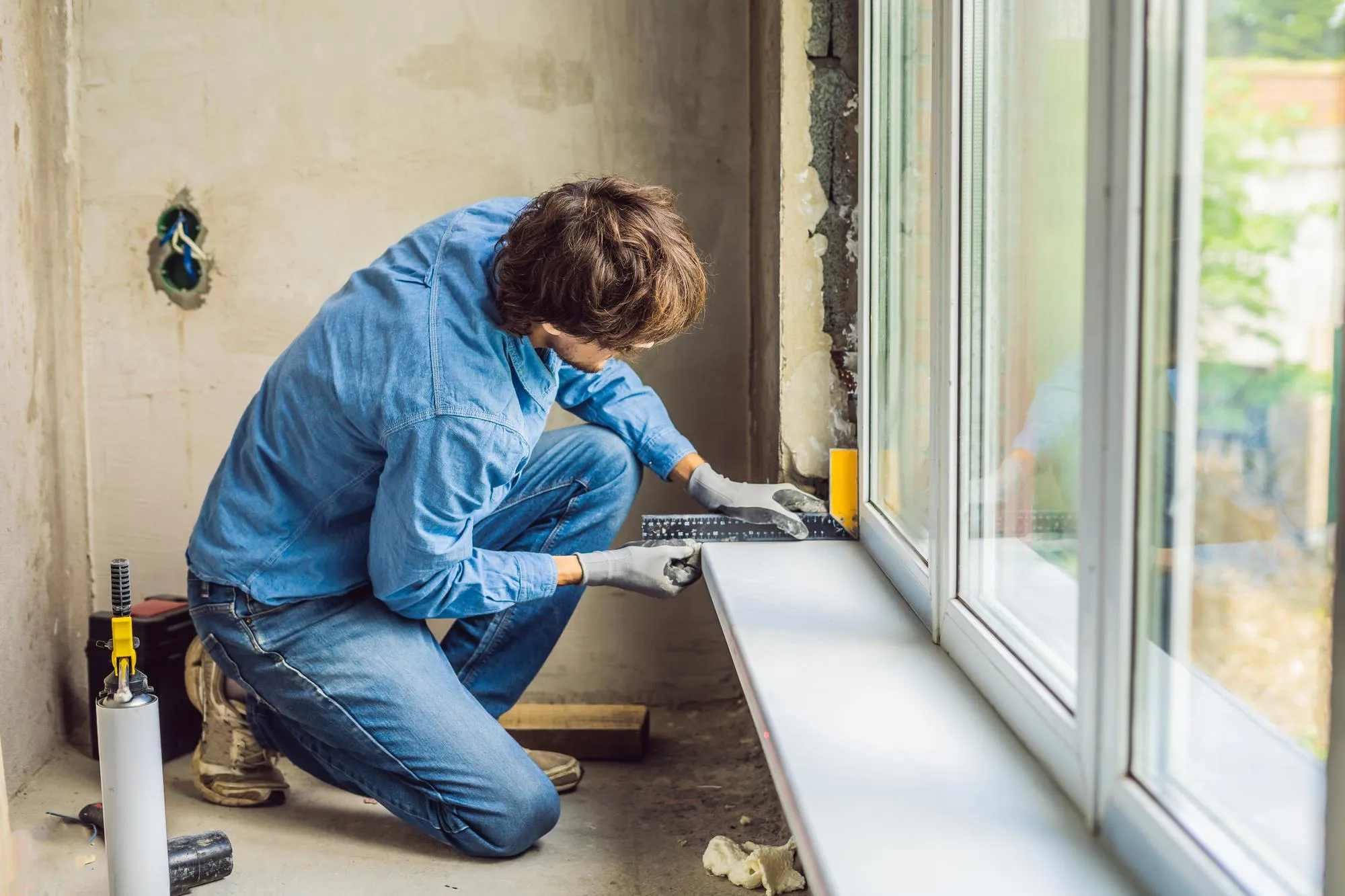 Man measuring and adjusting window frame carefully