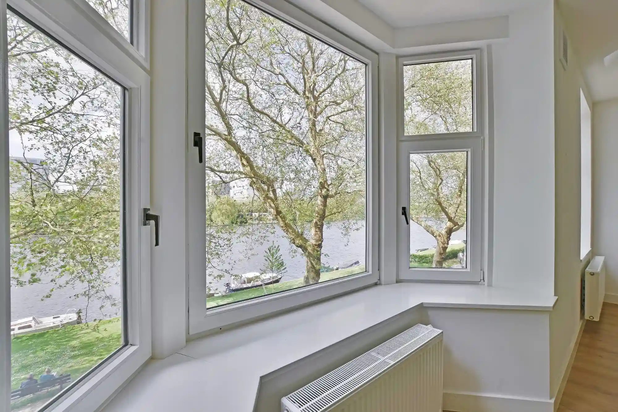 White casement windows with scenic outdoor river view White casement windows with scenic outdoor river view